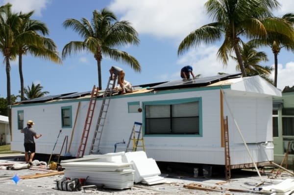 Solar panel installation on container home, construction in progress, palm trees